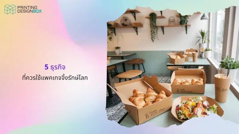 5 รูปแบบกล่องรีไซเคิลแพคเกจจิ้งที่คุณต้องลองใช้ รูปภาพภายในร้านกาแฟทันสมัยที่มีกล่องกระดาษบรรจุขนมปังครัวซองต์และผักสลัดบนโต๊ะไม้, แก้วน้ำกระดาษ, พื้นหลังมีผนังตกแต่งด้วยต้นไม้สีเขียว